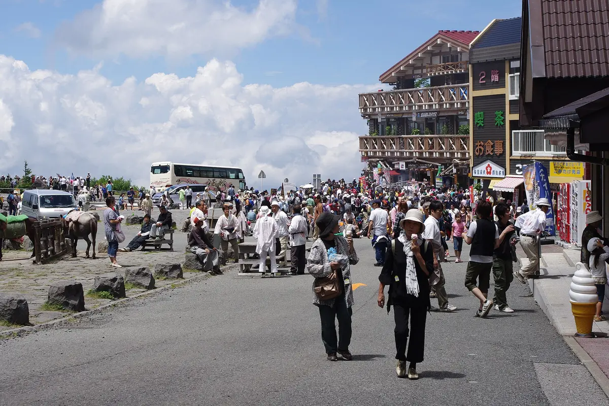 Shops, rest houses and crowds at the Mount Fuji 5th Station on the Kawaguchiko side, with a coach and cloud behind