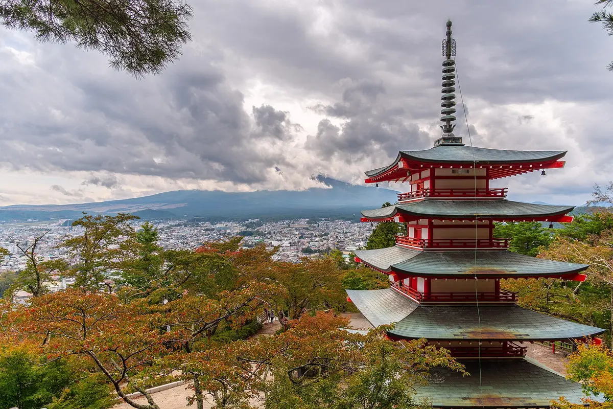 The Chureito Pagoda above autumn trees, with the summit of Mount Fuji hidden in cloud beyond the town of Fujiyoshida